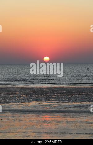 Beautiful sunset on the sea with iridescent colors on the surface of the water Stock Photo