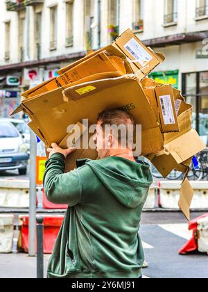 Man carrying flattened scrap cardboard boxes on shoulder and head - Tours, Indre-et-Loire (37), France. Stock Photo