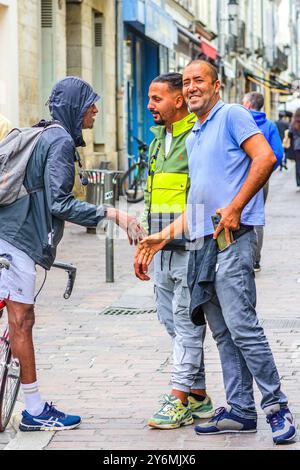 Three men / workers shaking hands in greeting in city center - Tours, Indre-et-Loire (37), France. Stock Photo