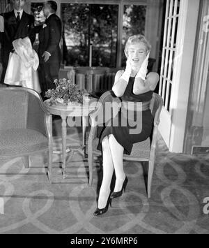 London: The girl who disorganised London Air sport yesterday, Marilyn Monroe, claps her hands to her ears to shut out the noise as Newsman fire questions at the 'Shape' from every angle. Marilyn is seen at the Savoy hotel where she held a press conference also there was her husband of a fortnight, Mr Arthur Miller, and Sir Laurence Olivier, with whom she is to film 'The Sleeping Prince'. Monroe and her husband had travelled to London from their retreat at Englefield Green, Surrey. While in England the couple will Honeymoon. 15 July 1956 Stock Photo