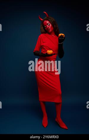 This woman embraces Halloween, wearing a bold costume and playfully interacting with pumpkins. Stock Photo