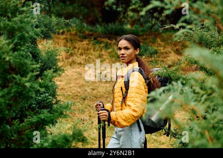 A young woman enjoys hiking through a colorful autumn forest, surrounded by lush greenery and golden leaves. Stock Photo