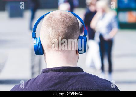 Man from behind, wearing headphones in city center Stock Photo