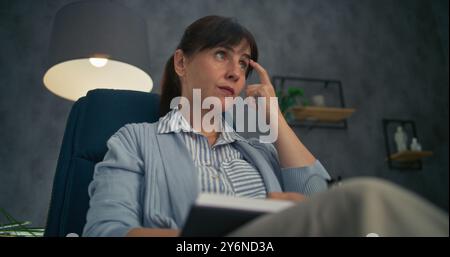 Close up of professional therapist sitting in chair, listening attentively to patient, taking notes in notebook. Female psychologist conducts counseling or therapy session. Psychological assistance. Stock Photo