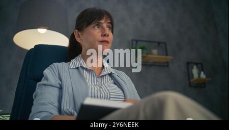 Close up of professional therapist sitting in chair, listening attentively to patient, taking notes in notebook. Female psychologist conducts counseling or therapy session. Psychological assistance. Stock Photo