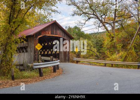 Historic one lane covered bridge spanning a river in the mountains on a cloudy autumn day. Stock Photo