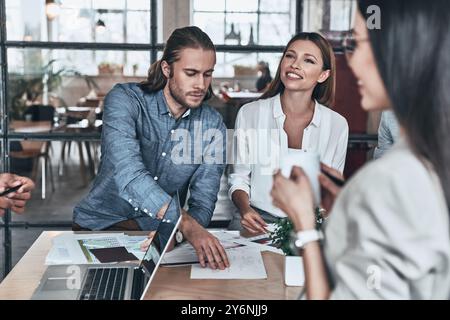 Going over details. Group of young business people working and communicating while sitting in the office Stock Photo