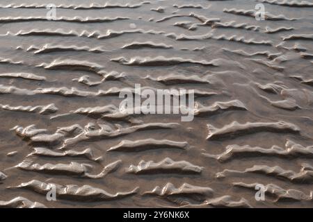 Textured sand patterns created by the receding tide, showcasing the artistry of nature. Stock Photo