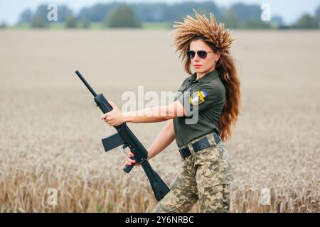 Female soldier in military uniform. A girl in a military uniform with a weapon. Ukrainian woman in a wreath. Stock Photo