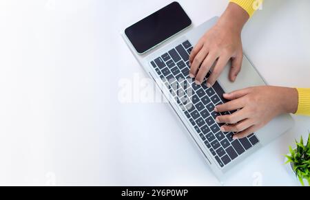 Office desk clean and minimal working scene with businesswoman hands over a silver laptop keyboard on a white office table in workplace, Top view, Cop Stock Photo