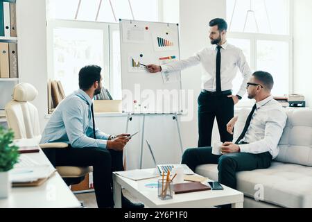 Developing new strategy. Young modern man in formalwear conducting a business presentation using flipchart while working in the office Stock Photo