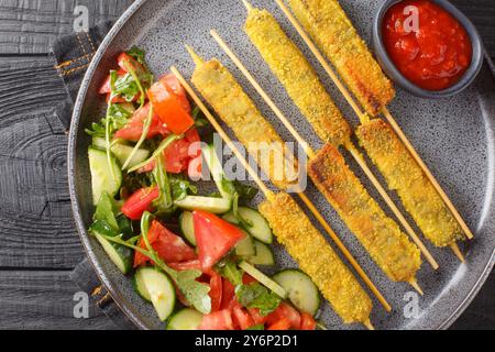 Vegetarian Breaded Eggplant Sticks served with vegetable salad and tomato sauce close-up on a plate on a table. Horizontal top view from above Stock Photo