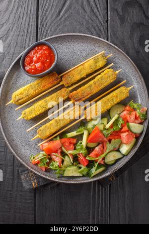 Fried Eggplant Sticks alla milanese in breading served with fresh salad close-up on a plate on a table. Vertical top view from above Stock Photo