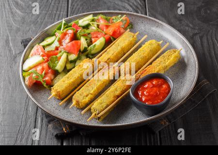 Vegan Kebab Sticks Breaded Eggplant Served with Vegetable Salad and Tomato Sauce Close-up on Plate on Wooden Table. Horizontal Stock Photo