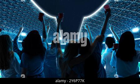 Group of fans raising their hands and cups, cheering in open-air stadium under night sky, with bright stadium lights glowing around them. Stock Photo