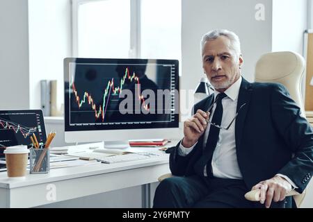 Senior trader in elegant business looking at camera while working at the office Stock Photo