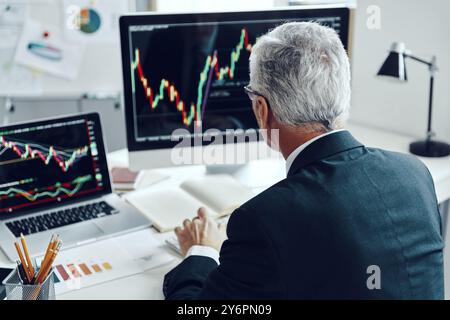Top rear view of senior trader in elegant business suit using computer while working at the office Stock Photo