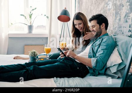 Happy together. Beautiful young couple having breakfast while spending time in bed at home Stock Photo