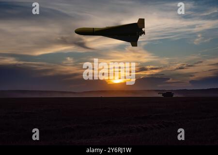 A Russian military drone flying over a peaceful field, evening lighting. Stock Photo