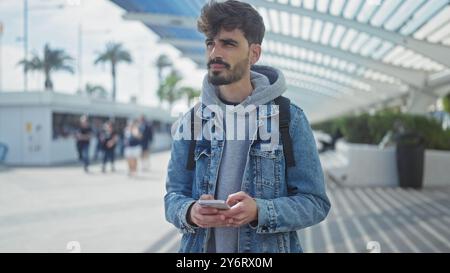 Handsome young hispanic man with beard using smartphone on city street Stock Photo