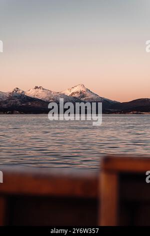 Sunset sky behind snowy mountains in the arctic next to fjord in Tromso, Norway Stock Photo