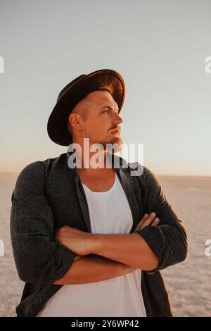 portrait of young tanned blonde European courageous man with beard barefoot, boho hat style. Ukrainian landscape sunset, famous places of Ukraine pink Stock Photo