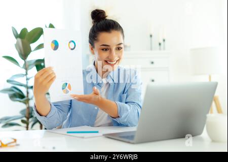 Online business conference.Confident indian or arabian woman, company boss, sit at workplace with laptop, having online business networking with coworkers, shows presentation by video call with client Stock Photo