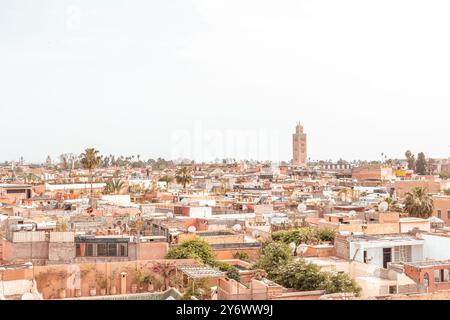 A panoramic view of Marrakech cityscape featuring prominent Kutubiyya Mosque tower, rooftops, palm trees, in the historic Medina, taken from Le Jardin Stock Photo