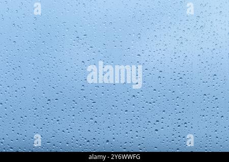 Drops of rain accumulate on a window, blurring the view outside and creating a peaceful ambiance, reflecting the tranquility of a rainy afternoon. Stock Photo