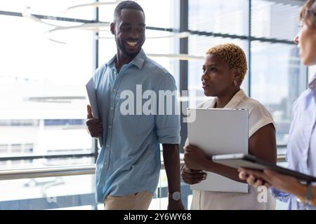 Business colleagues walking and discussing work, holding documents in modern office Stock Photo