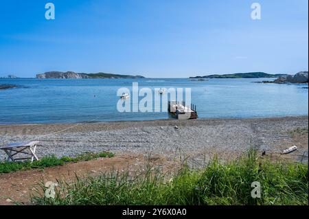 calm waters in a sheltered bay with boats moored off from the dock. Stock Photo