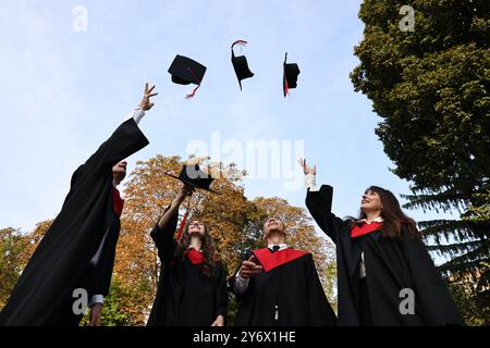 Graduation ceremony. Group of students throwing hats outdoors, low angle view Stock Photo