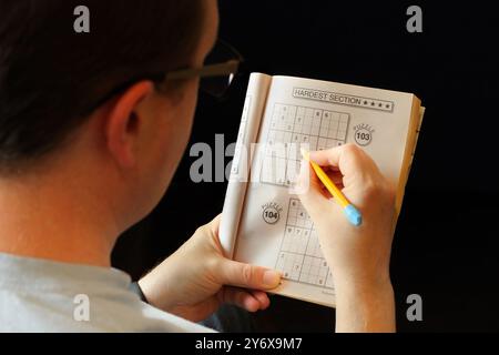 Over the shoulder image of man doing sudoku puzzle Stock Photo