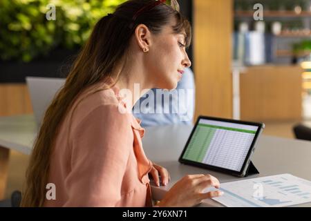 Analyzing data on tablet, woman working in modern office environment Stock Photo