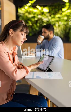 Using tablet for work, woman analyzing data while african american man working on laptop Stock Photo