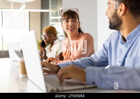 Working in office, colleagues using laptops and discussing project at desk Stock Photo