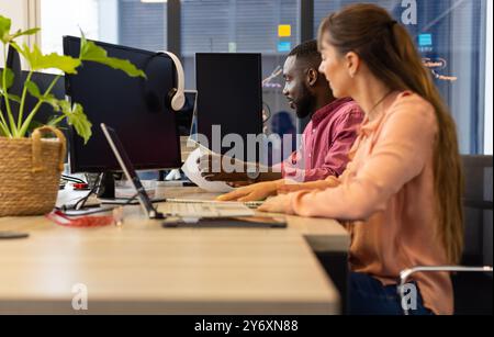 Working in office, colleagues collaborating on project using computers and documents Stock Photo