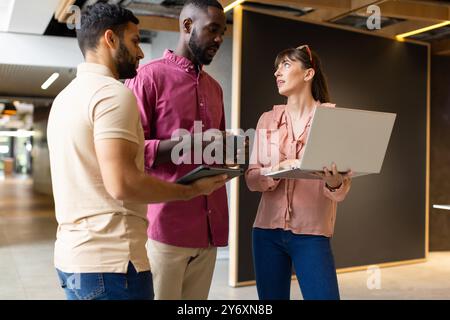 Business colleagues discussing project, using laptop and tablet in modern office Stock Photo