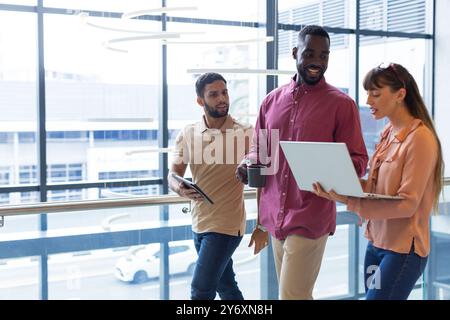 Discussing work, diverse colleagues using laptop and tablet in modern office, copy space Stock Photo
