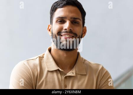 Smiling man in casual shirt posing confidently with arms crossed indoors Stock Photo