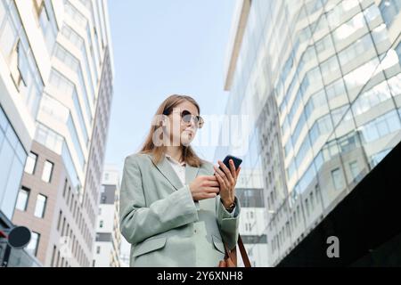 Young Woman In Sunglasses Using Smartphone Stock Photo