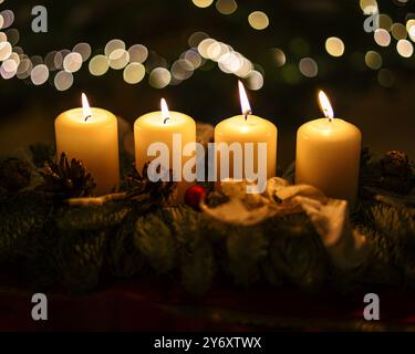 A candle holder with four candles in it. The candles are lit and the holder is on a table with title space bottom Stock Photo
