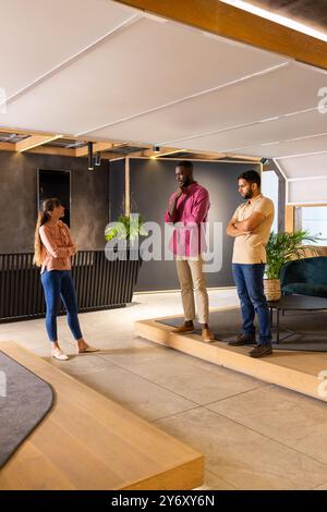Discussing project ideas, three colleagues standing in modern office space Stock Photo