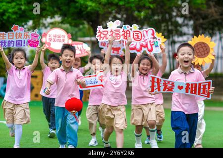 Beijing, China's Jiangsu Province. 26th Sep, 2024. Children run with blessing signs in hand at a kindergarten in Xinghua City, east China's Jiangsu Province, Sept. 26, 2024. Various activities are held at kindergartens and primary schools across the country to welcome the upcoming 75th anniversary of the founding of the People's Republic of China. Credit: Zhou Shegen/Xinhua/Alamy Live News Stock Photo