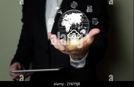 Businessman holding a holographic globe with technology icons representing global business and cloud computing. Stock Photo