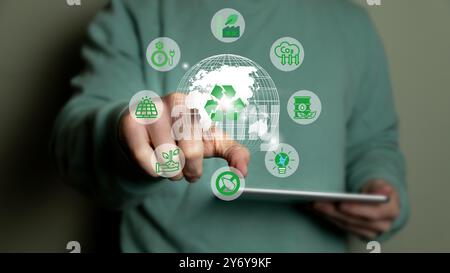 A person interacting with a digital interface displaying various eco-friendly icons around a globe, emphasizing sustainability and green technology. Stock Photo