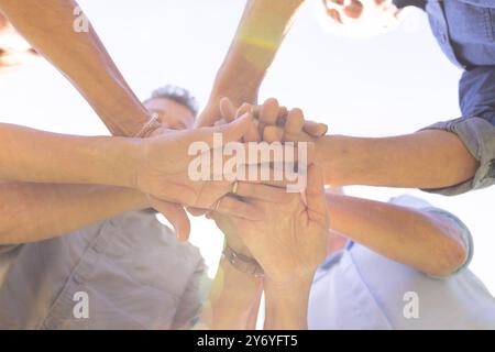 Senior diverse friends stacking hands together, showing unity and teamwork outdoors, at home Stock Photo