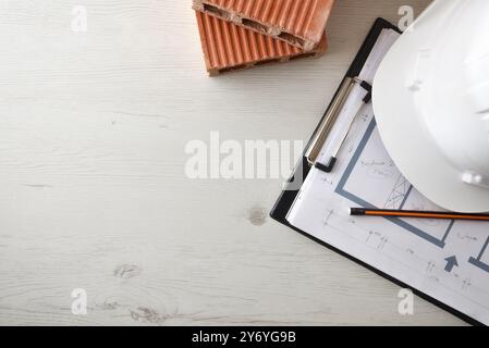 Conceptual background of architect's table with house plan with notes, protective helmet and bricks. Top view. Stock Photo