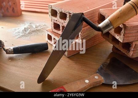 Background with construction tools on wooden board with bricks pile of cement powder. Elevated view. Stock Photo