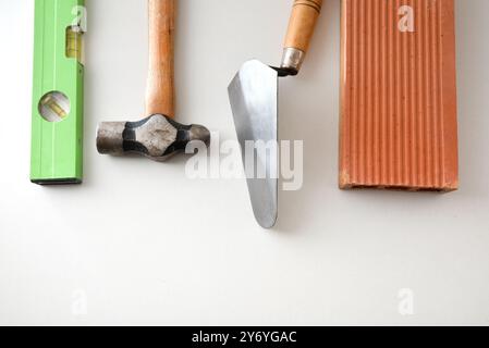 Construction tools such as trowel, level, hammer and brick isolated on white background. Top view. Stock Photo